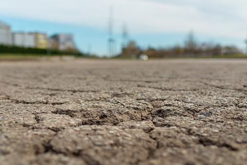 Empty damaged alphalt road in the street.Blurred blue sky background.Selective focus,Close-up.