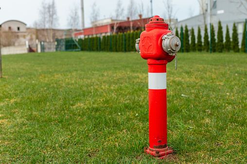 Single red fire hydrant on green lawn,near factory.Autumn,spring,summer day.Copy space.