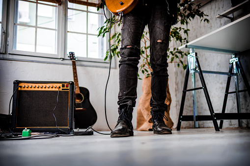 Legs of guitarist next to amplifier while practices electric guitar
