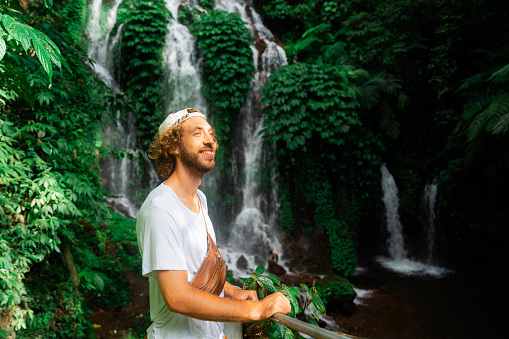 Portrait of cheerful man enjoying tropical waterfall  on Bali