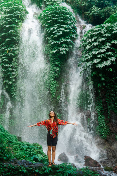 istock Woman standing near the refreshing waterfall on Bali 2077692410