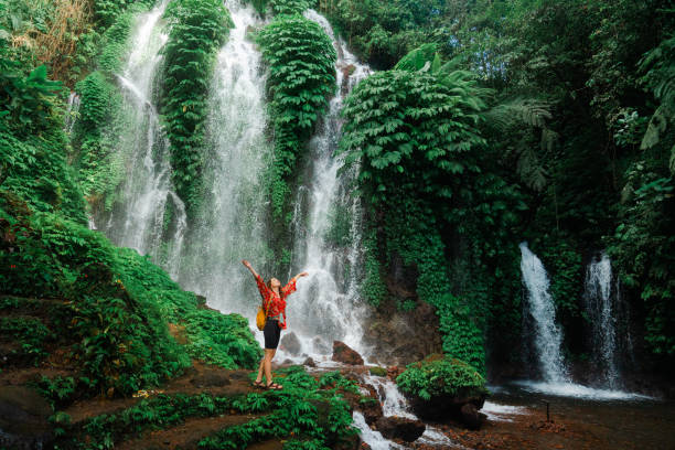 istock Woman standing near the refreshing waterfall on Bali 2077692412