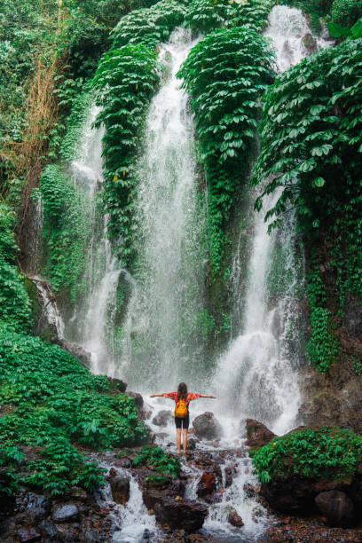Woman standing near the refreshing waterfall on Bali