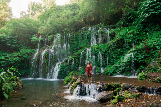 istock Woman standing near the refreshing waterfall on Bali 2077697672