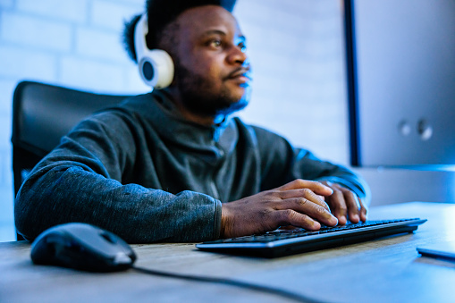 Black gamer playing online video game on personal computer