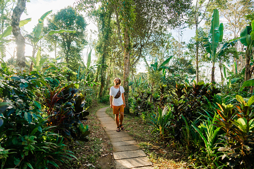 Serene man  walking on path through tropical garden enjoying sunny day