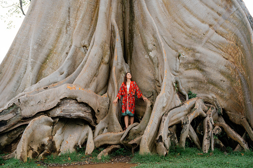 Serene woman in touch with nature enjoying interaction with giant banyan tree on Bali