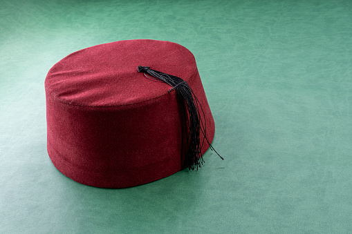 Turk fez hat on green leather. Turkish cultural concept idea.