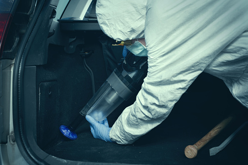 Criminologist technician collecting evidence with vacuum and micro filter