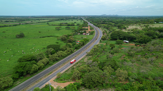 Aerial: Red Coca-Cola truck driving through green tropical landscape in Panama. Transport vehicle delivering refreshing drinks while travelling along the longest driveable road that connects Americas.