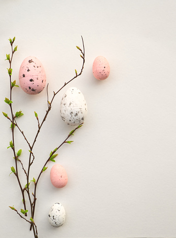 Colorful Easter eggs with cherry blossoms flat lay on white background. Stylish tender spring template with space for text. Greeting card or banner