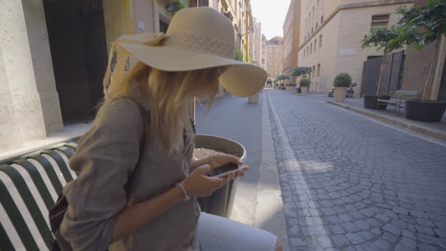 Woman text messaging on mobile phone in the street of Rome, Italy ; People travel capital in Europe concept