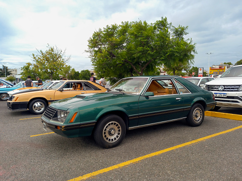 Buenos Aires, Argentina - Feb 25, 2024: Old green shiny sport 1980s Ford Mustang hatchback Fox body two door sedan at a classic car show in a parking lot. Side view. Copy space