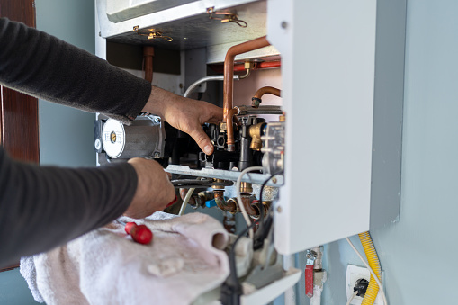 Technician Repairing Natural Gas Combi Boiler At Home