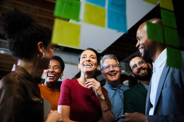 istock Laughing businesspeople having an office brainstorming session using a adhesive notes 2077799117