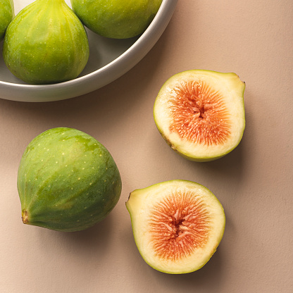 Fresh figs on a soft beige, powdery background. Seasonal fruits, healthy eating, eco market, top view, square crop