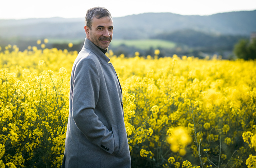 Portrait of an elegant mature man surrounded by yellow flowers in a rapeseed field.
People, spring, lifestyle