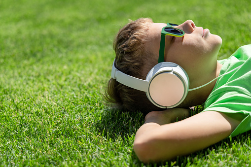 A boy relaxing on grass, listening to music with headphones