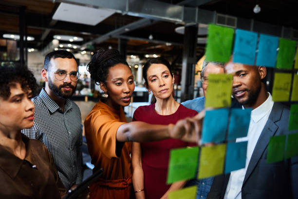 istock Diverse businesspeople brainstorming using adhesive notes on a glass wall in an office 2077814252