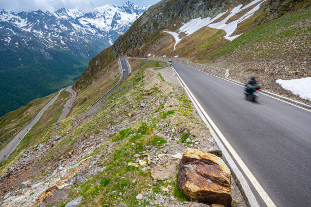 Alpine mountain road with cars driving through the hairpin corners along the Timmelsjoch high mountain pass during a beautiful springtime day in the Italian Alps of South Tirol.