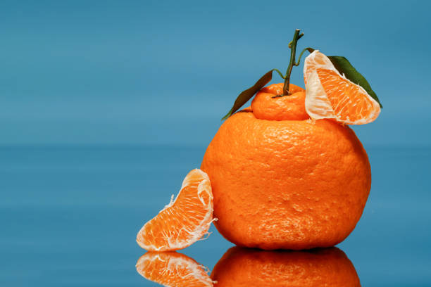 istock Tangerine with slices and leaves on a blue background. 2077817405