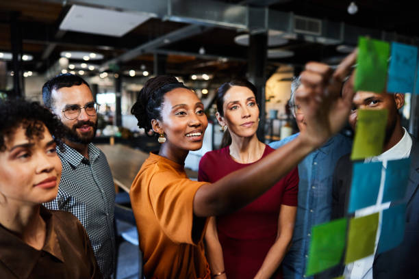 istock Smiling businesspeople having a brainstorming session using adhesive notes on a glass wall 2077824720