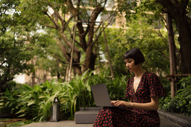 istock Young Asian woman using laptop in the park. 2077835195