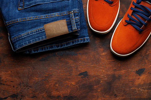 Men's Clothing on wooden Background: Jeans, Sneakers, Eyeglasses, Flat Lay with Copy Space