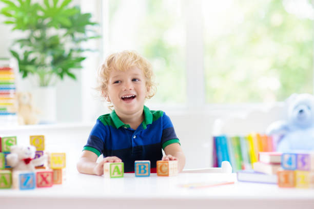 istock Child learning letters. Kid with wooden abc blocks 2077866095