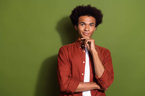 retrato fotográfico de un buen joven toca la barbilla pensativa confiada en vestir ropa marrón de moda aislada sobre fondo de color caqui - men button down shirt black smug fotografías e imágenes de stock