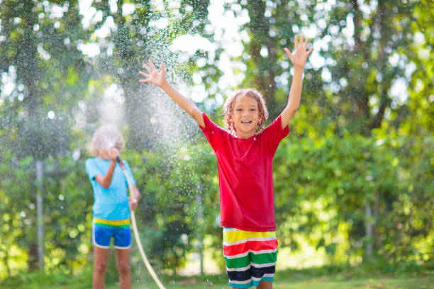 istock Kids play with water sprinkle hose. Summer garden 2077924470
