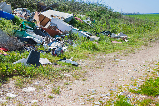 Illegal dumping with bottles, boxes and plastic bags abandoned in nature