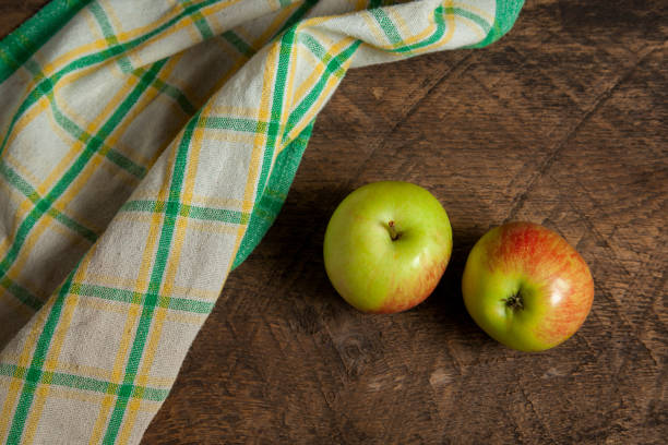 istock Two green apples on wooden background with green kitchen towel. 2077931869