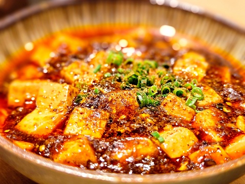 Tofu cubes serving in a bowl, seasoned with black and white sesame and chopped scallion