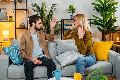 Young couple with relationship problems arguing on the sofa in the living room.