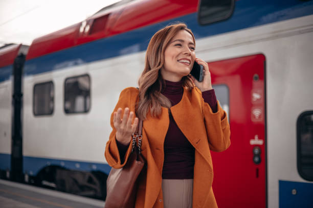 istock Happy woman using cell phone while waiting at subway platform 2077981878