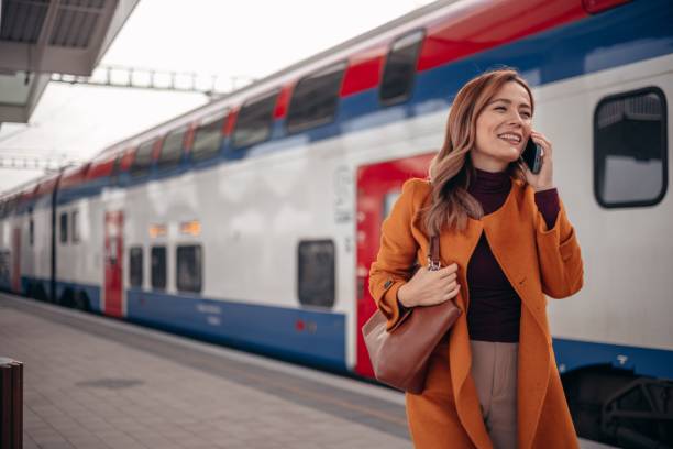 istock Happy woman using cell phone while waiting at subway platform 2077982383