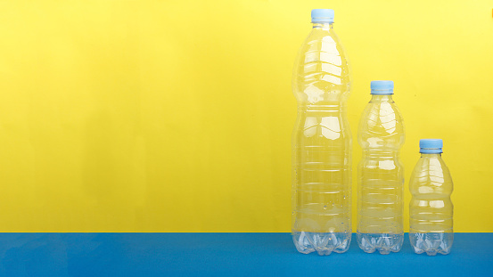 Three Plastic bottles from PET Polyethylene Terephthalate material against yellow blue background