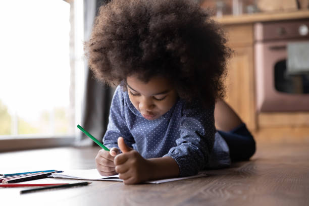 istock African girl lying on floor in kitchen draw in sketchbook 2078041383