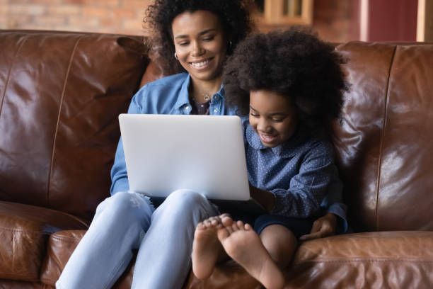 istock African mother and daughter sit on sofa with wireless computer 2078046546