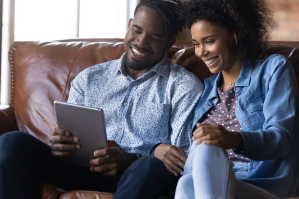 istock Laughing African couple watch video on digital tablet 2078048630
