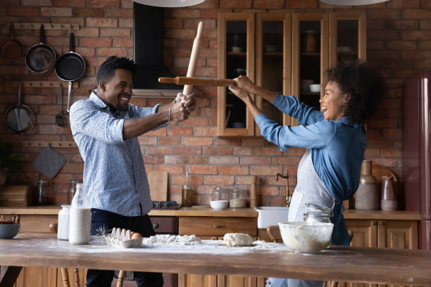 istock African couple have fun in kitchen holding rolling pins fighting 2078071610