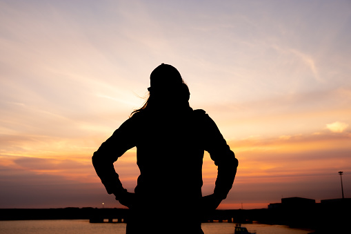 silhouette of an unrecognizable girl at sunset in a port
