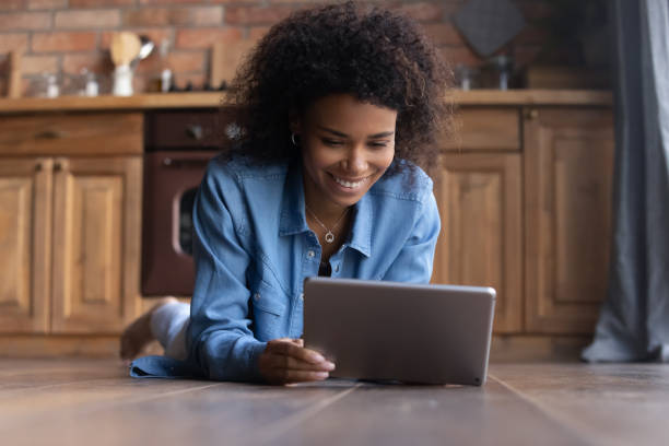 istock Smiling African woman lying on floor with digital tablet 2078091073