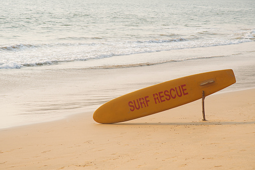 Yellow lifeguard surf rescue board by the ocean on the sand