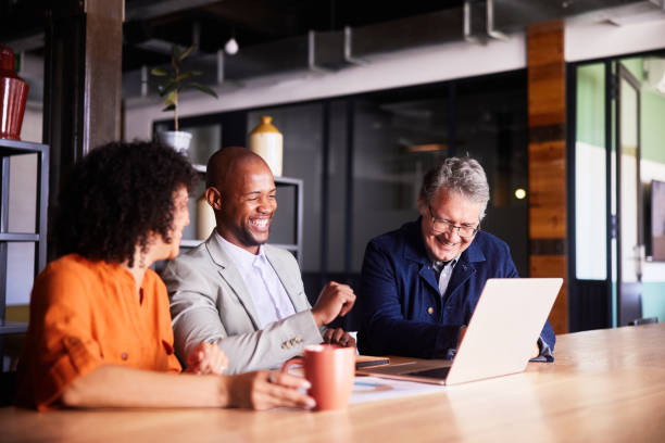 istock Diverse businesspeople laughing while working on a laptop in an office 2078125374