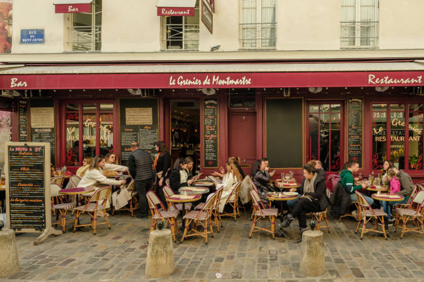 Paris, France - February 17, 2024 : View of people sitting outdoors and enjoying dinner and drinks at a restaurant bistro in Montmartre Paris France
