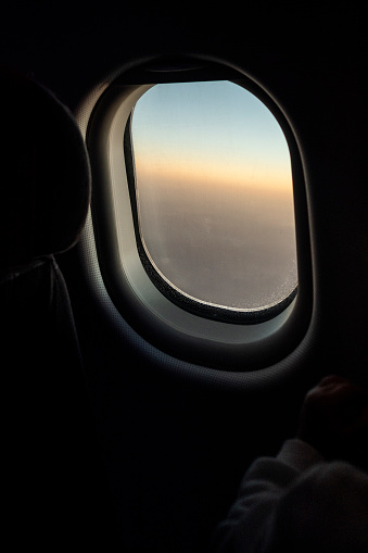 Airplane window in mid-flight. From the inside you can see the wing of the plane. Sunset