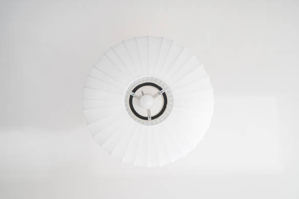 Low angle shot of white ceiling lamp in lampshade with energy saving bulb against bright surface. Concepts of home lighting and room decor, directly below view