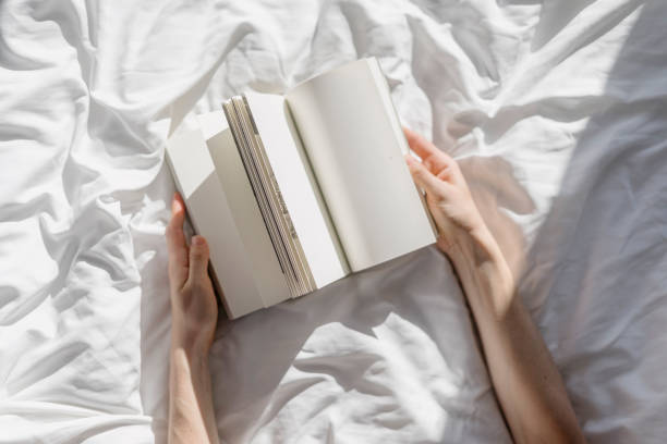 istock Top view on woman hands hold paper notebook with empty pages while lying in bed 2078160030